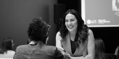 Woman smiling while talking to someone across a table.