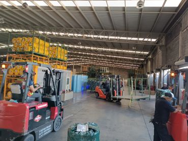 Interior de una bodega con montacargas y materiales apilados.