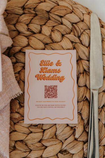 A wedding invite card on a woven placemat with a knife.