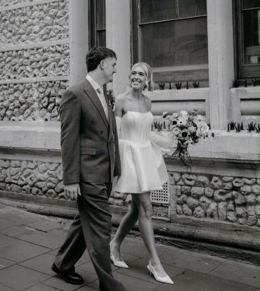 Couple walking happily, bride holding flowers.