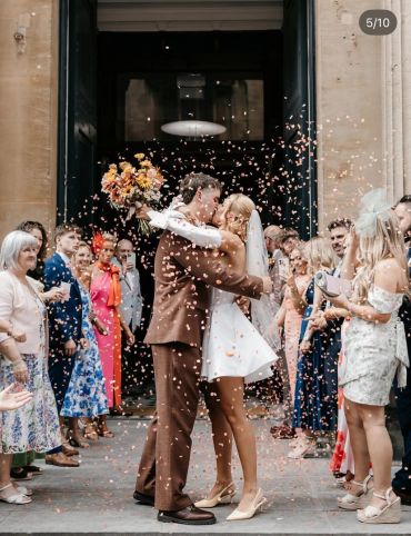 Newlyweds kiss as petals shower around them.