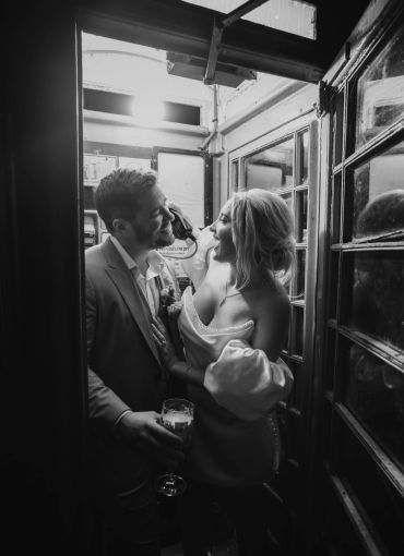 Couple enjoying a moment in a phone booth at night.