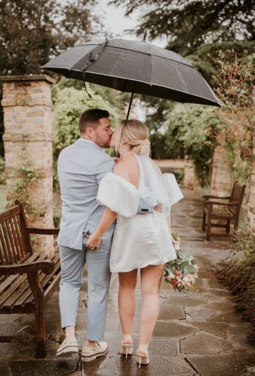 Couple kissing under an umbrella in the rain.