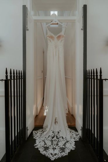 Elegant white wedding dress hanging in a doorway.