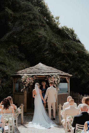 Couple holding hands during outdoor wedding ceremony.