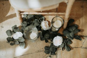 White roses and candles under a chair on a tiled floor.