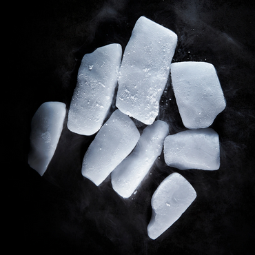 Close-up of irregular ice cubes on a dark background with frost.