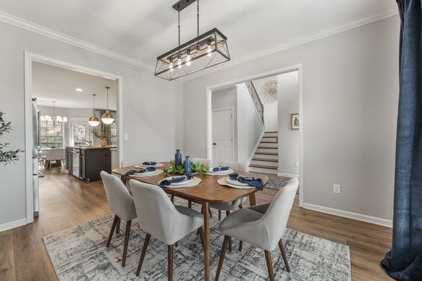 Modern dining room with wooden table and gray chairs under a geometric light fixture.