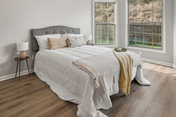 Cozy bedroom with a neatly made bed and large windows letting in natural light.