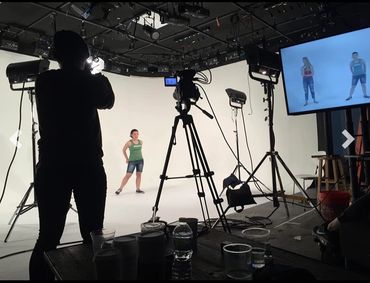 Filming session in a professional studio with a model and camera crew.