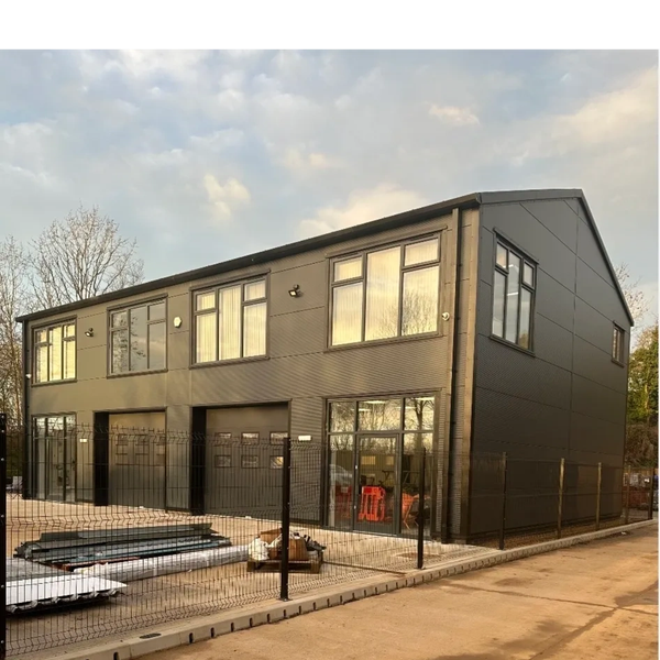Modern black commercial building with large windows and fenced perimeter.
