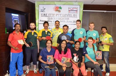 Group photo of table tennis coaches holding paddles and certificates.