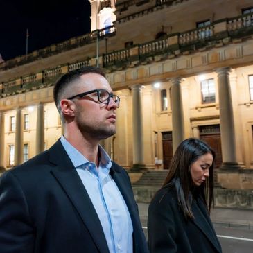 Two people walking outside a historic building at night.