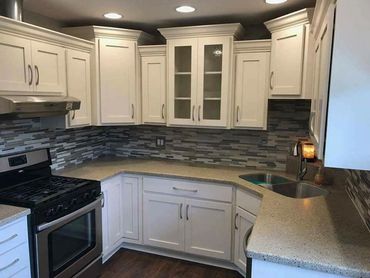 Modern kitchen with white cabinets and a gray tiled backsplash.