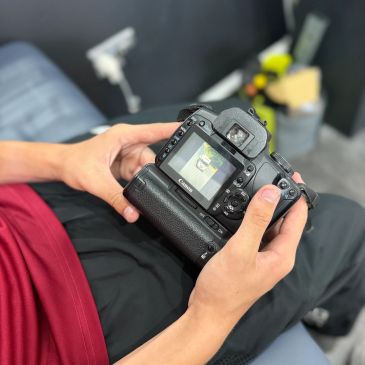 Person holding a Canon camera displaying an image on its screen.