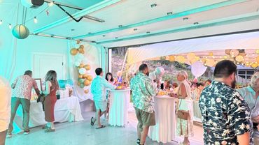 People socializing at a decorated indoor-outdoor party with balloons and lanterns.