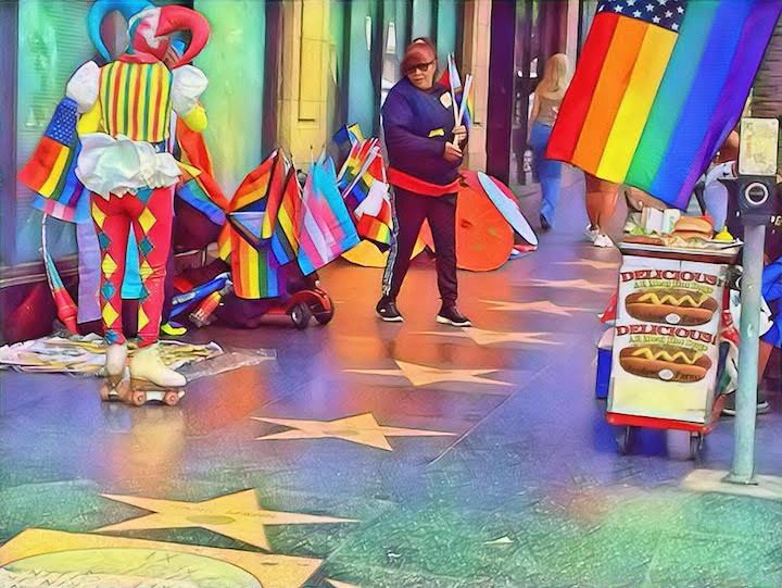 Colorful street scene with pride flags and a jester on roller skates.