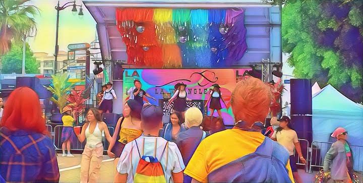Crowd watching a vibrant LGBTQ+ pride event with rainbow decorations and performers.