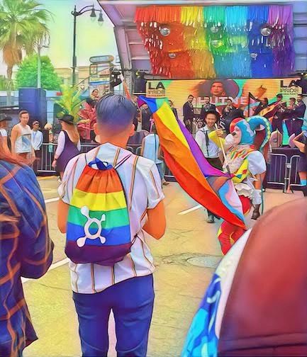 Colorful pride event with rainbow flags and performers in vibrant costumes.