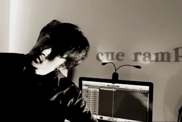 Person in front of a computer screen with text on the wall behind.