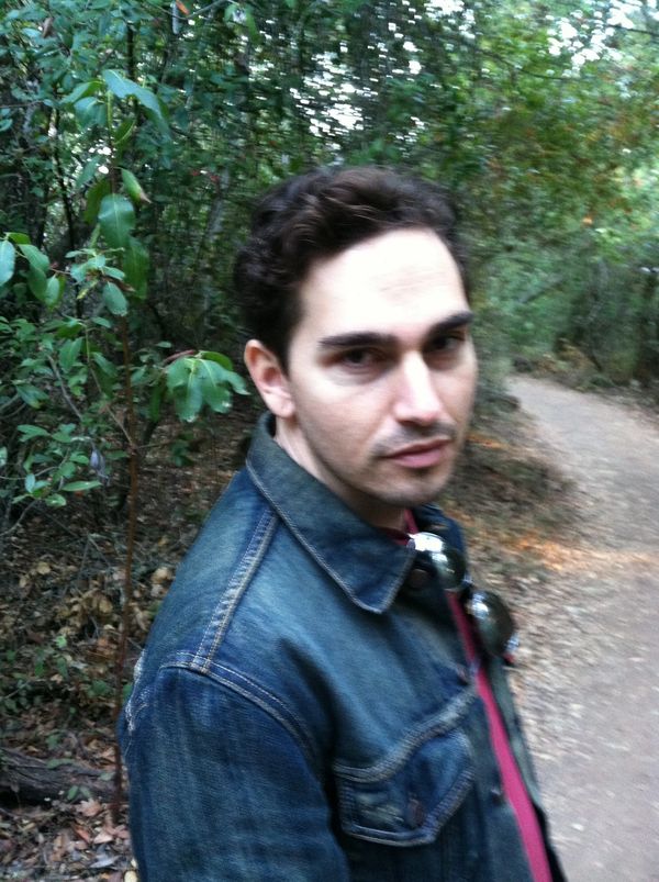 Man in denim jacket walking on a forest trail.