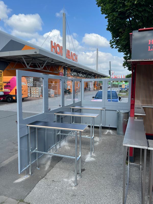 Outdoor seating area with transparent dividers near a store.