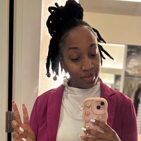 Woman with dreadlocks takes a mirror selfie showing a peace sign.