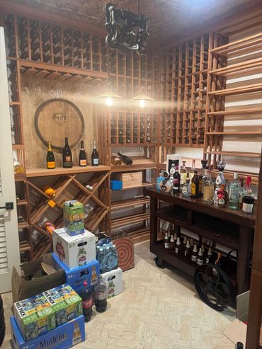 Elegant home wine cellar with wooden racks, stocked with various drinks and beverages.