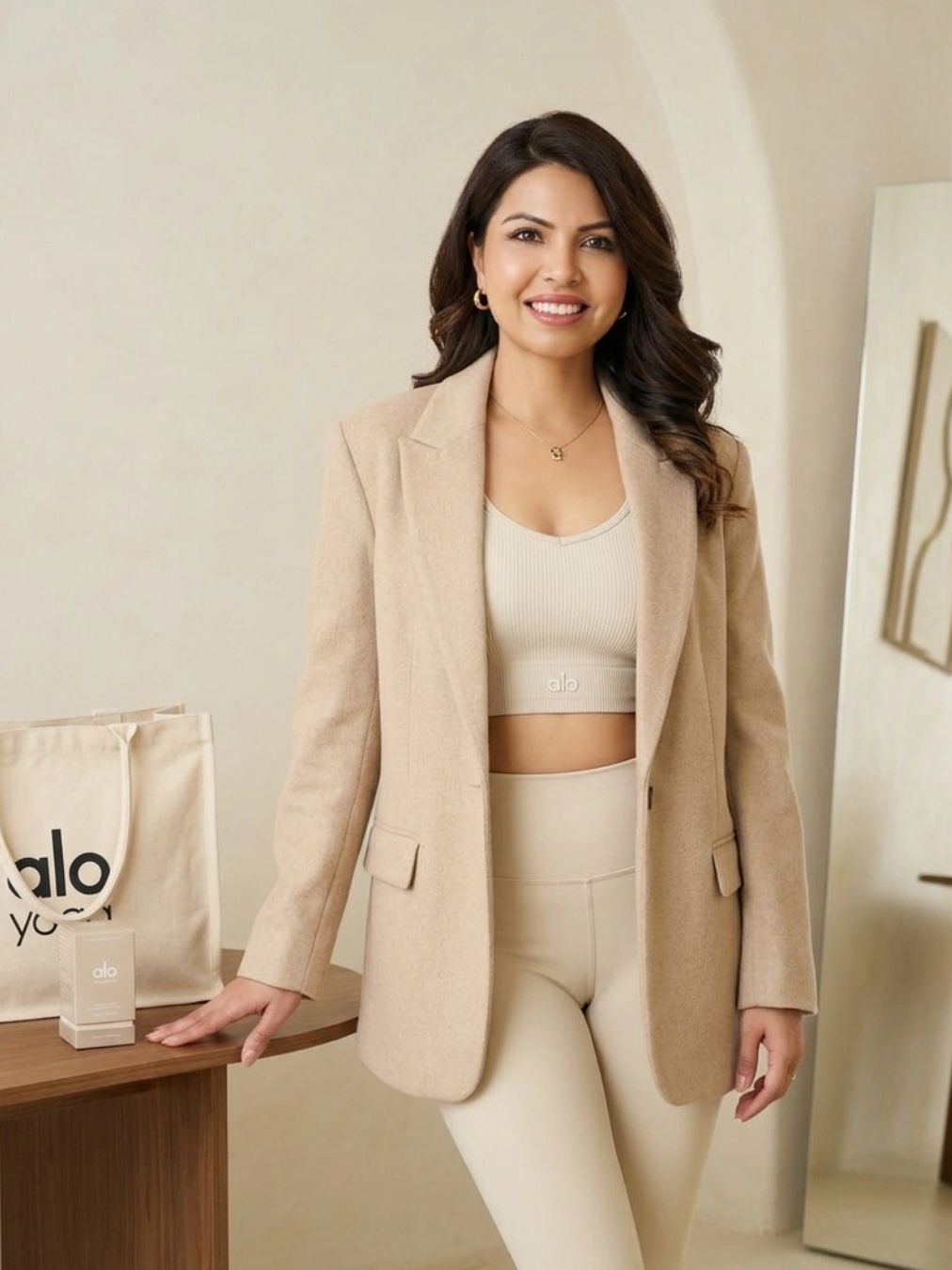 Woman in beige blazer and activewear smiling indoors.