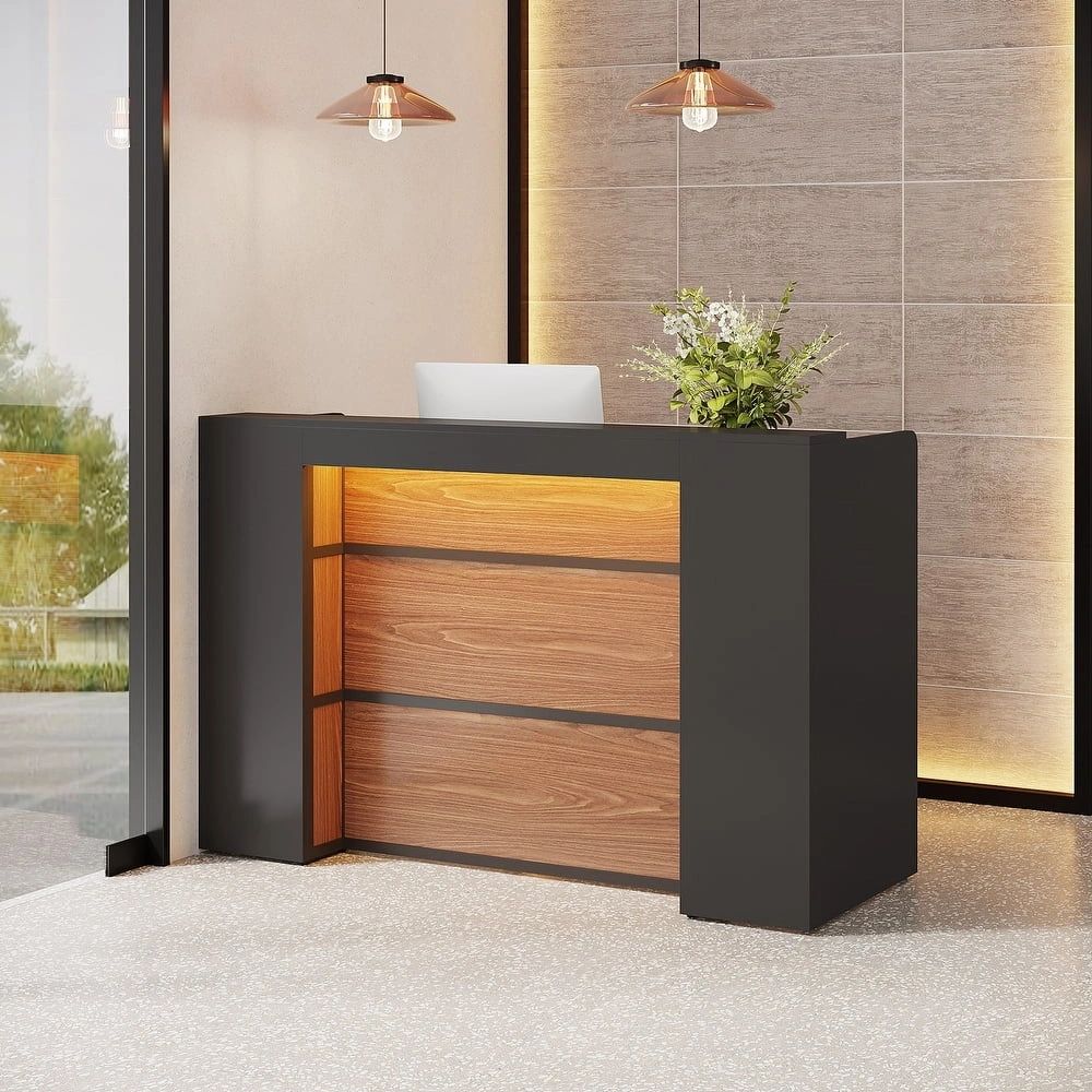 Modern reception desk with warm wood and black accents in a bright, stylish lobby.
