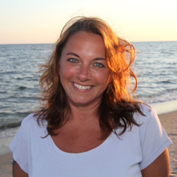 Smiling woman at beach during sunset.