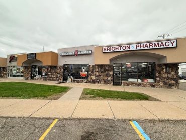 A strip mall with stores including Brighton Pharmacy and Electric Ramen.