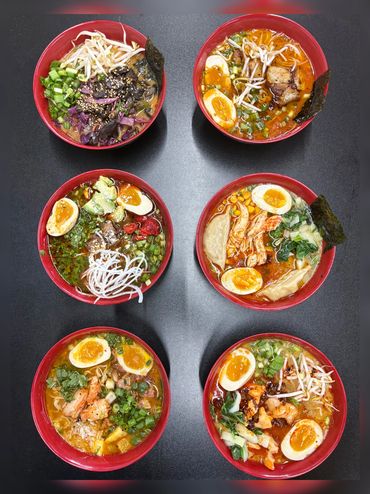 Six red bowls of ramen with various toppings on a black table.