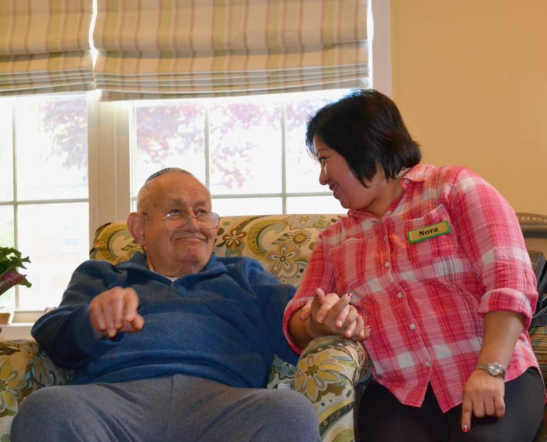 Resident and caregiver holding hands and smiling while engaging in activity