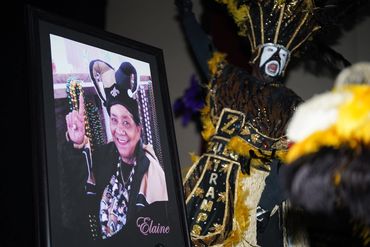 Portrait of Elaine beside a lively Mardi Gras Indian performer in vibrant costume.