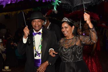 A joyful couple dressed in formal attire holding umbrellas and celebrating.