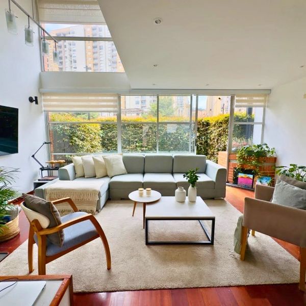 Bright and modern living room with large windows and cozy seating.