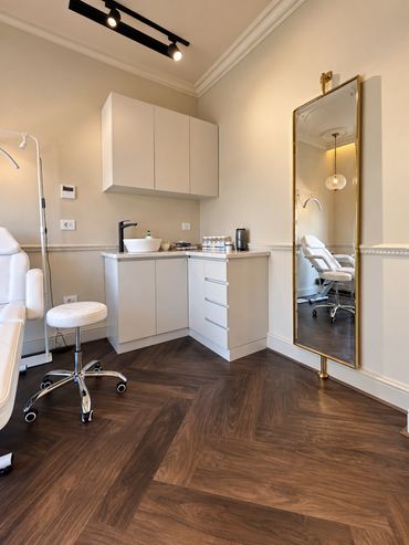 Treatment room with brass-framed mirror - Deasalus Clinic, Mivida - تصميم عيادات