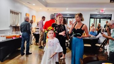 People socializing at an indoor event with drinks and casual attire.