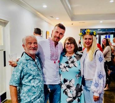 Four people smiling at a social gathering indoors.