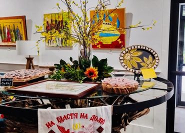 Art gallery table with Ukrainian cakes and floral decorations.