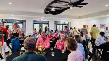 A lively social gathering with people chatting and enjoying drinks indoors.