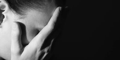 Person with hand on face, expressing distress or sadness in black and white.