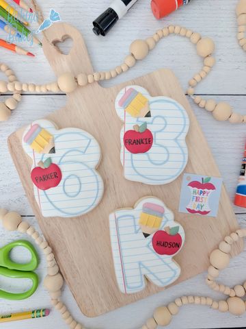 Decorated cookies shaped like letters and numbers with school-themed designs.