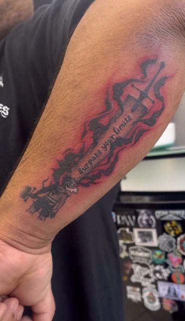 Forearm tattoo of a guitar with flames and text.