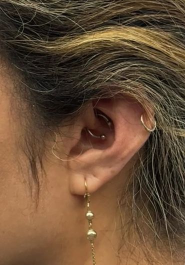 Close-up of an ear with multiple piercings and gold earrings.