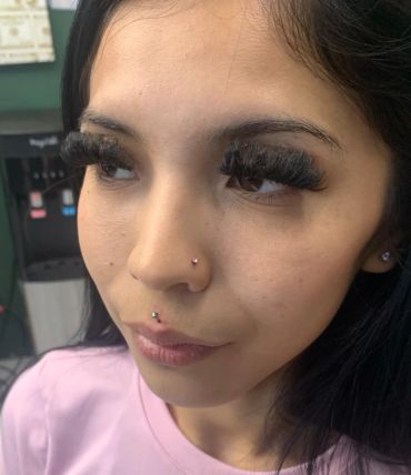 Woman with long eyelash extensions and facial piercings.