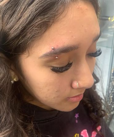 Young woman with eyebrow and nose piercings.