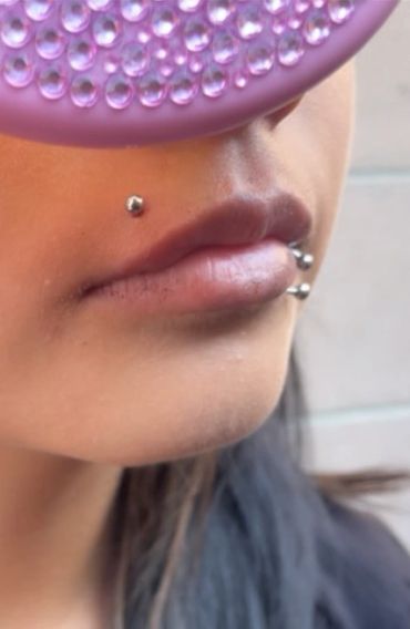Close-up of lips with multiple silver piercings.