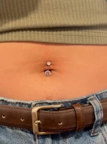 Close-up of a belly button piercing with rhinestones.